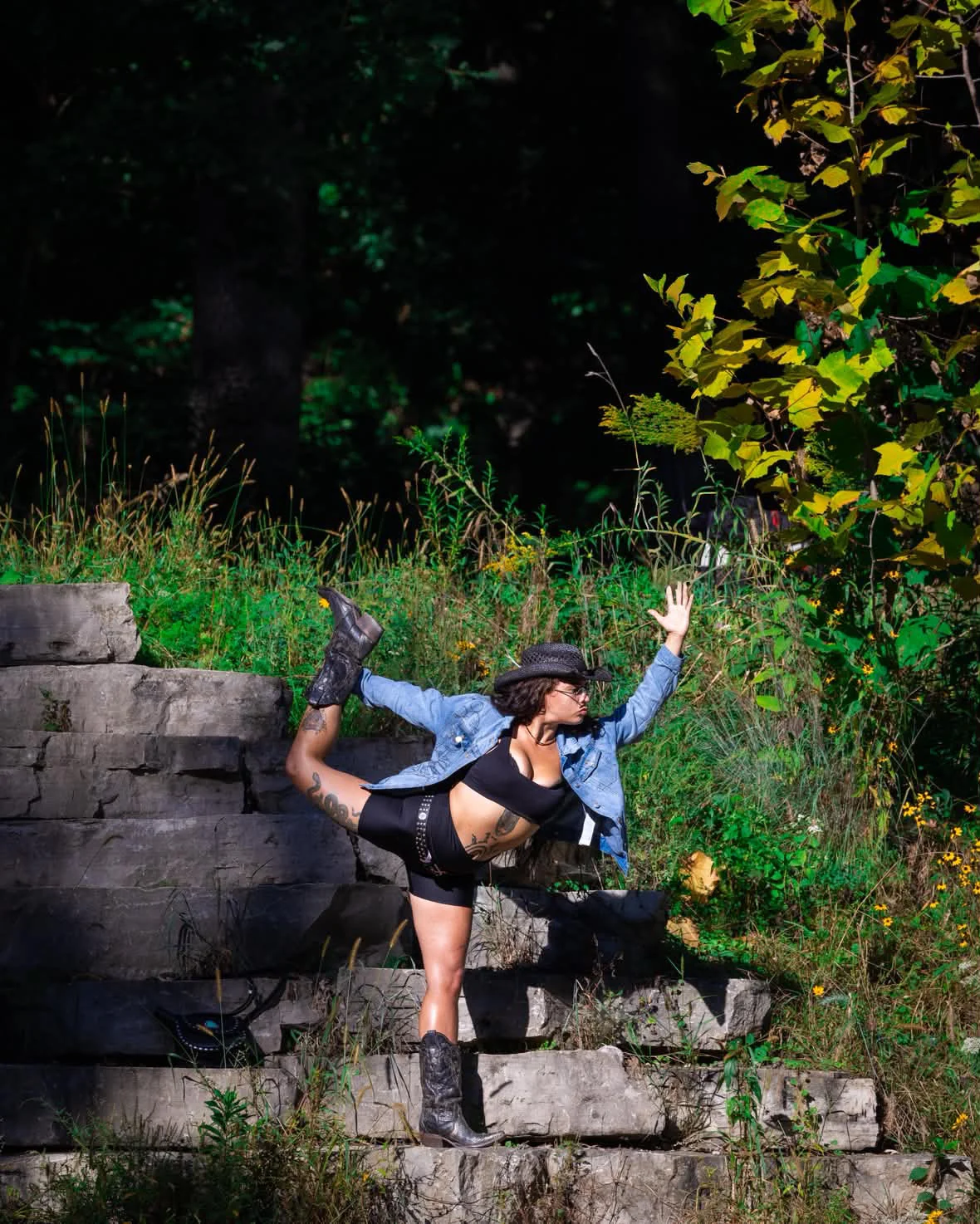Paige balancing in dancer pose on stone steps beside the river